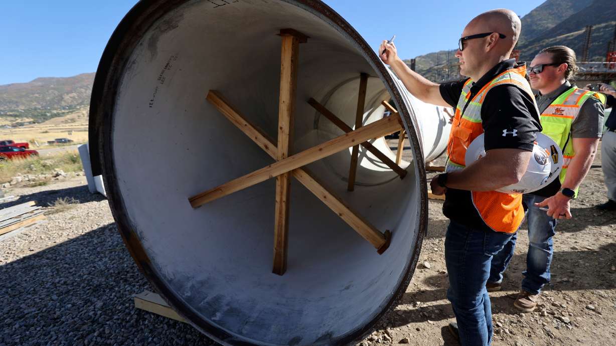 Sage Thorpe signs a 72-inch steel pipe that will be installed as part of an $81-million seismic resilience project for the Davis Aqueduct, to increase water security in the event of a major earthquake, in South Weber on Wednesday.