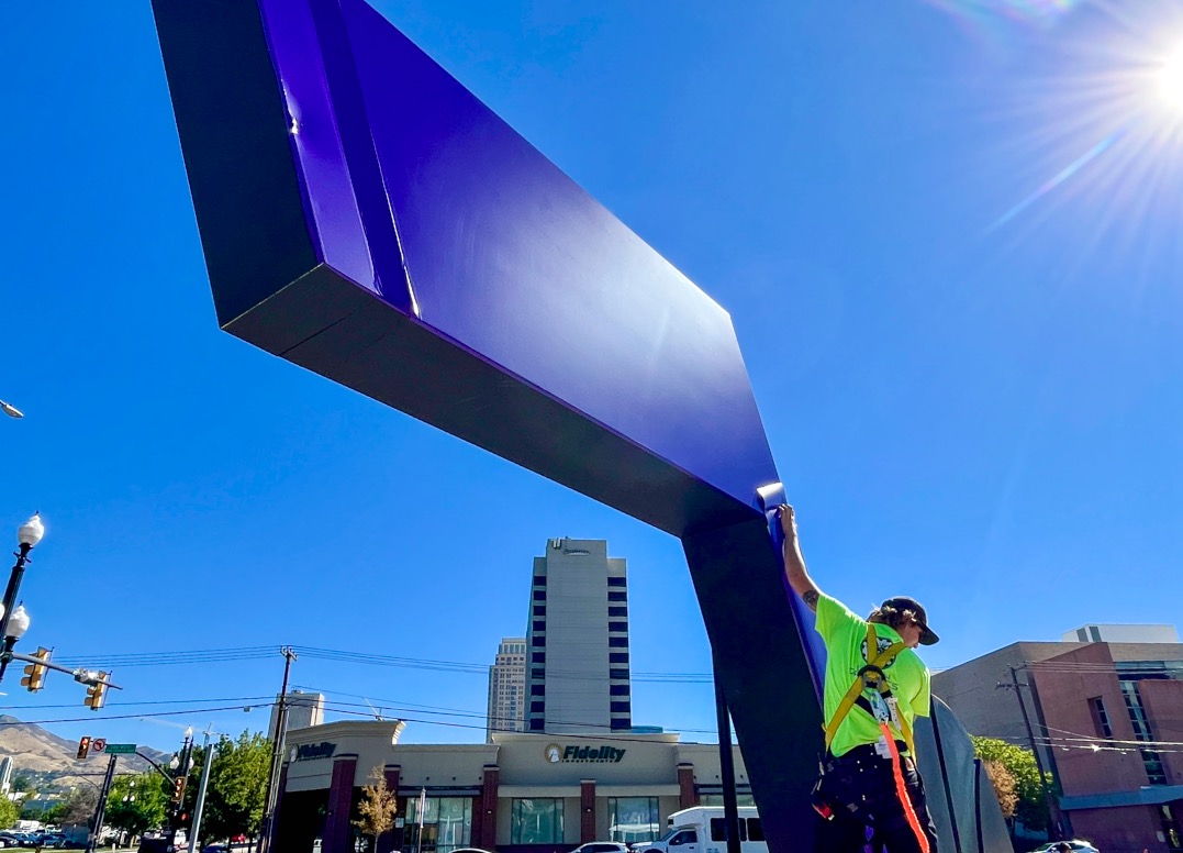 An employee adds a purple wrap to the J-Note statue outside of the Delta Center on Tuesday.