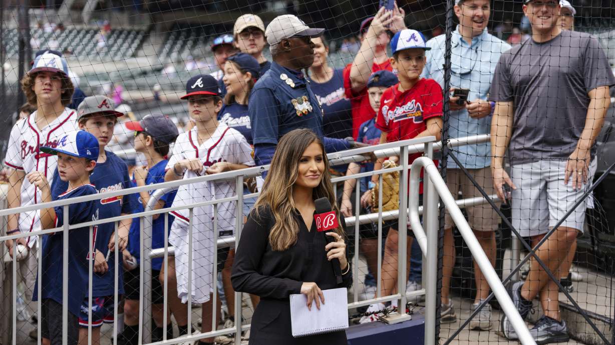 Bally reporter, Hanna Yates, broadcasts her pregame with fans standing behind her waiting for autographs before the start of a baseball game between the New York Mets and the Atlanta Braves, Monday, Sept. 30, 2024, in Atlanta.
