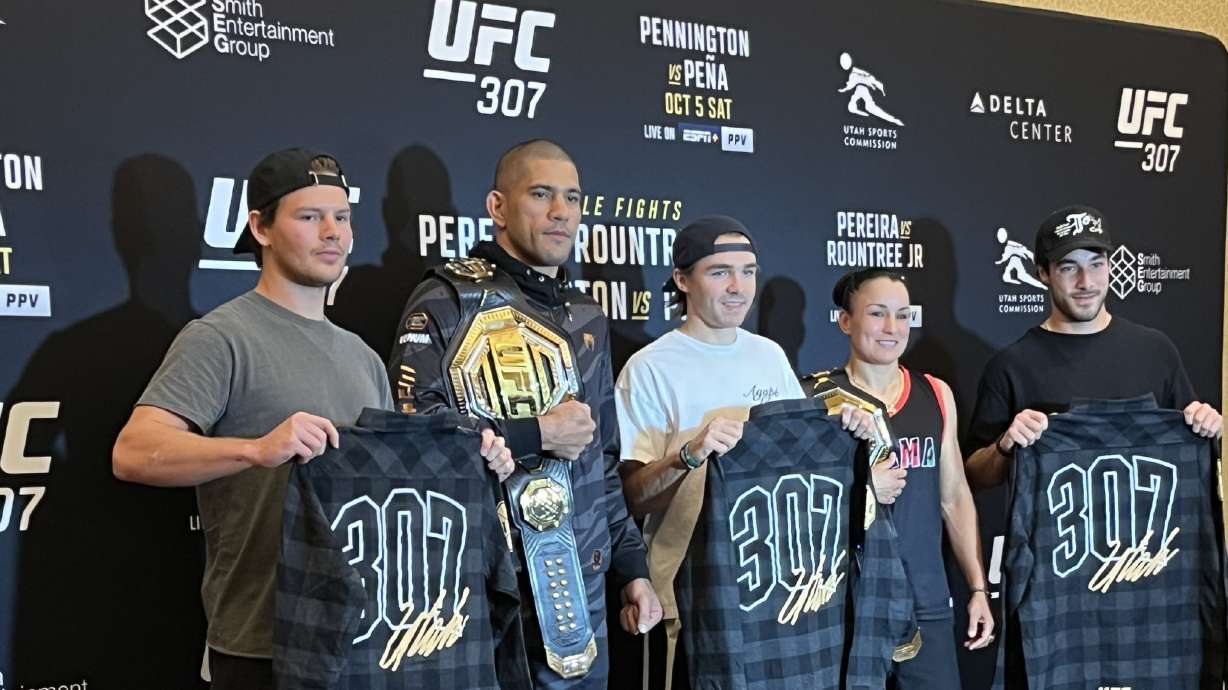 UFC champions Alex Pereira and Raquel Pennington pose for a photo with members of the Utah Hockey Club during media day for UFC 307 in Salt Lake City, Wednesday, Oct. 2, 2024.