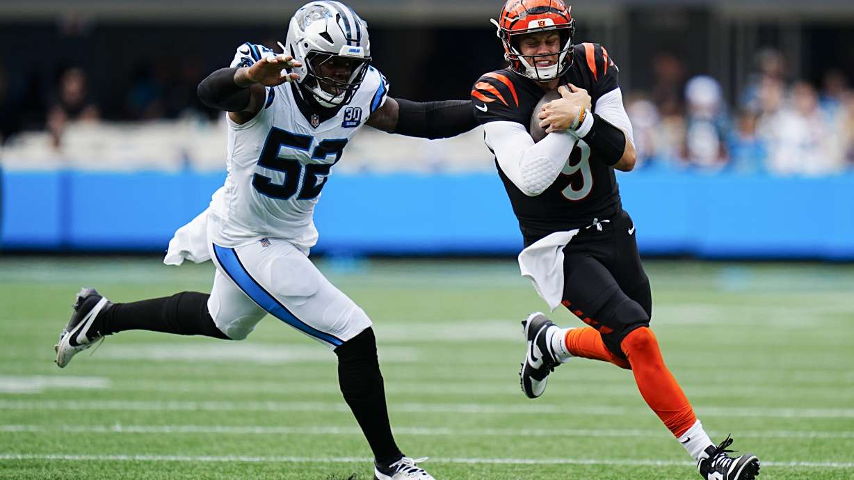 Cincinnati Bengals quarterback Joe Burrow runs past Carolina Panthers linebacker DJ Johnson during the first half of an NFL football game, Sunday, Sept. 29, 2024, in Charlotte, N.C.