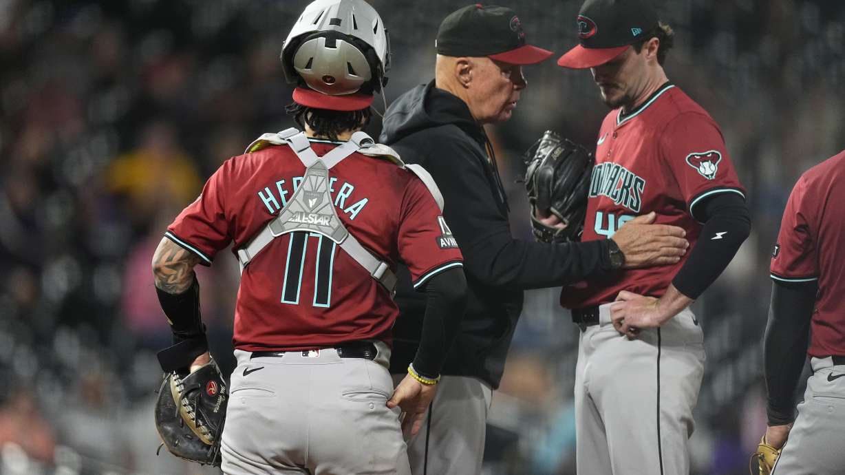 Arizona Diamondbacks pitching coach Brent Strom, center, confers with relief pitcher Blake Walston as catcher Jose Herrera looks on after Walston gave up an RBI single to Colorado Rockies' Brendan Rodgers in the eighth inning of a baseball game Tuesday, Sept. 17, 2024, in Denver.
