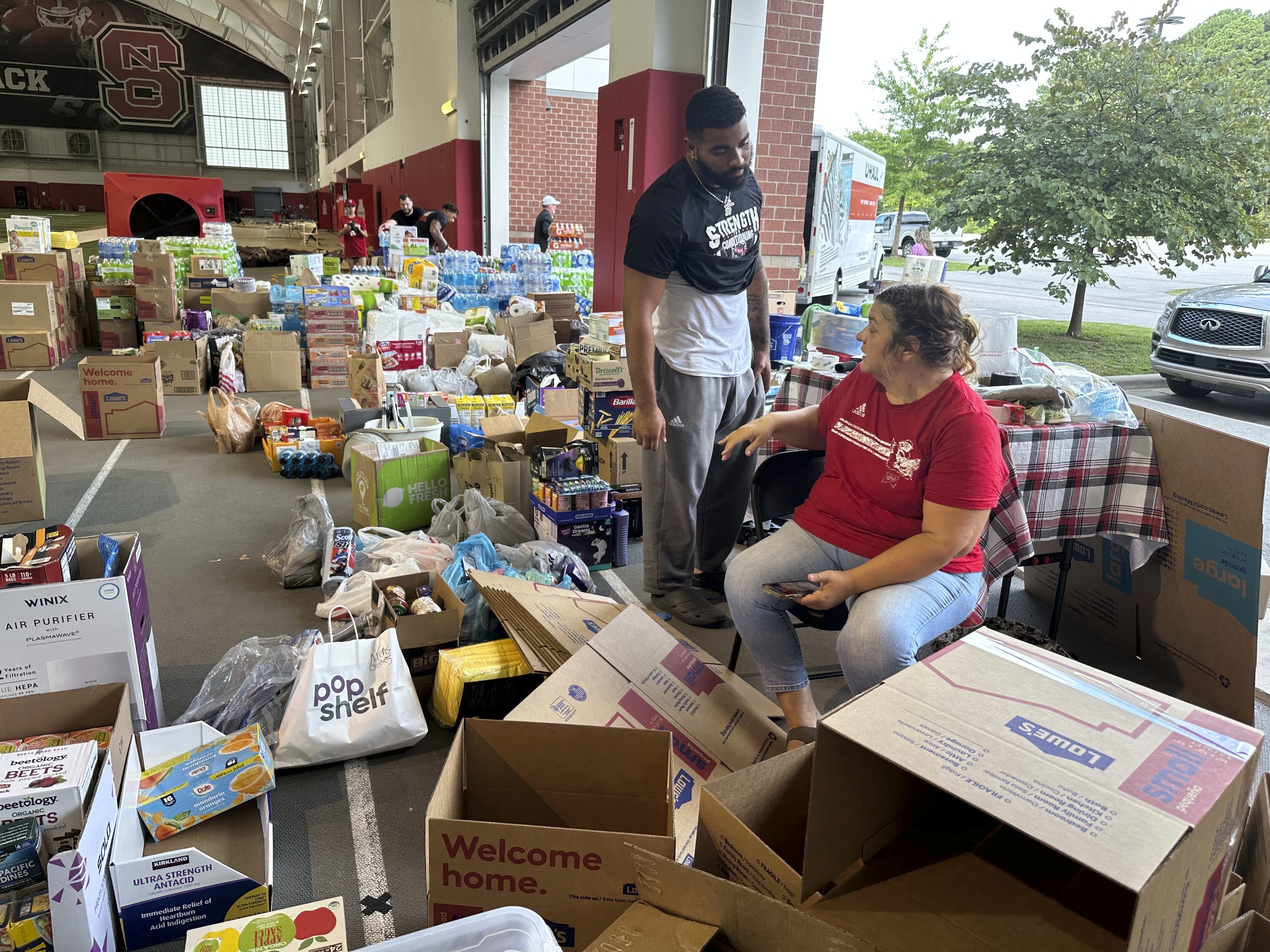 N.C. State defensive end Davin Vann and his mother, Joy Hall, work among the donations collected to help Hurricane Helene victims in western North Carolina, Wednesday, Oct. 2, 2024 in Raleigh, N.C.