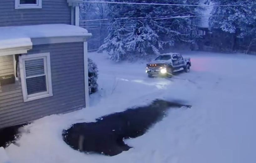 A truck slides perpendicularly down a snowy, icy road.