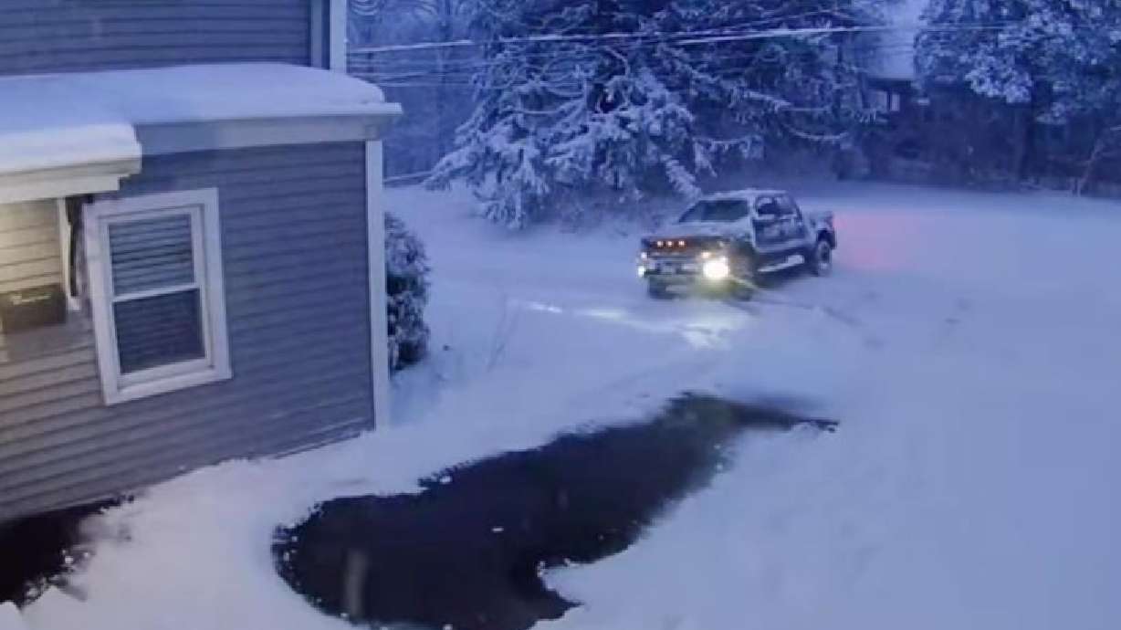 A truck slides perpendicularly down a snowy, icy road.