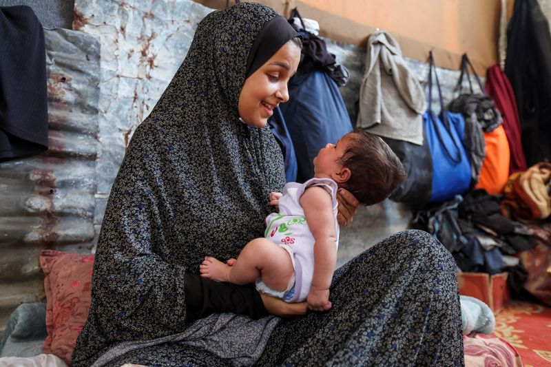 Displaced Palestinian mother Rana Salah holds her daughter Milana in a tent where they shelter, amid the Israel-Hamas conflict, in Deir Al-Balah in the central Gaza Strip, Sept. 10.