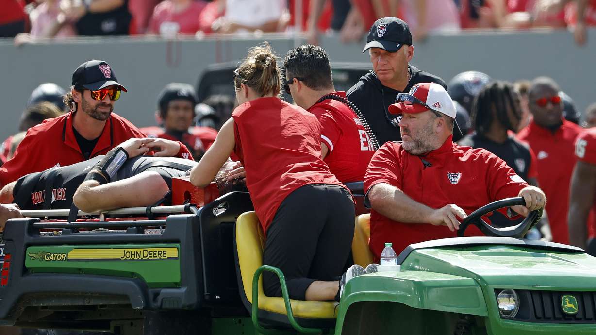 North Carolina State head coach Dave Doeren, rear right, checks on quarterback Grayson McCall (2) as he is carted from the field following an injury during the first half of an NCAA college football game in Raleigh, N.C., Saturday, Oct. 5, 2024.