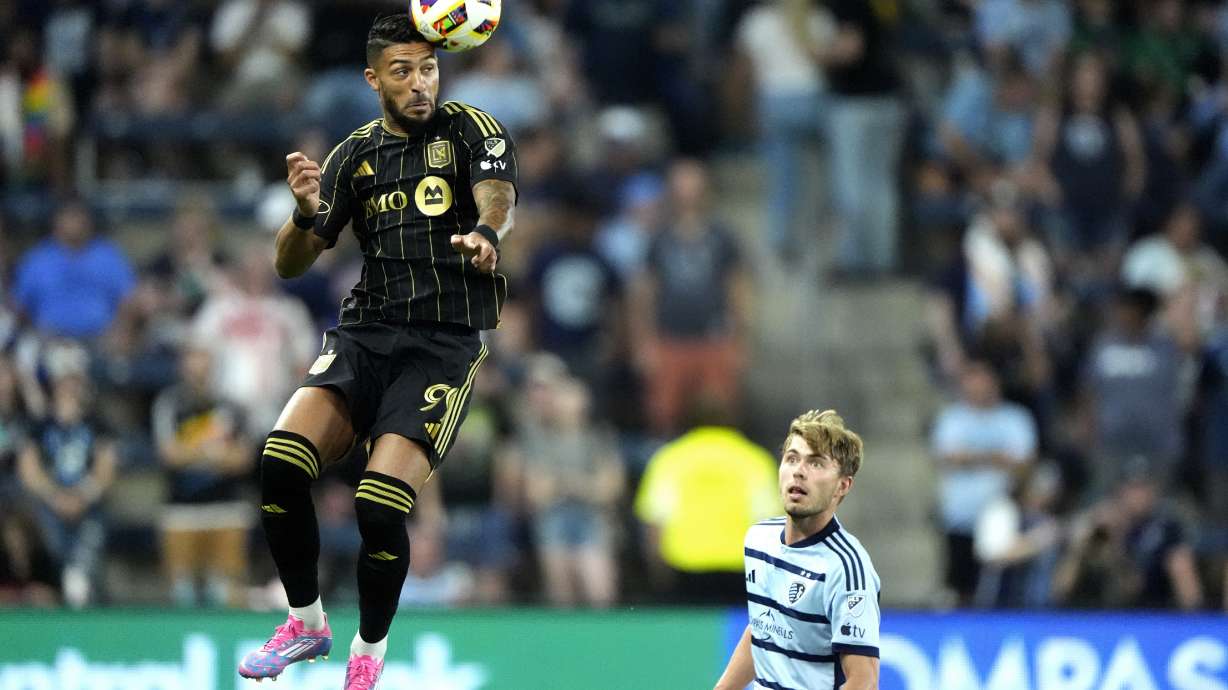 Los Angeles FC attacker Denis Bouanga, left, passes the ball over Sporting Kansas City defender Jake Davis during the first half of an MLS soccer match Saturday, Oct. 5, 2024, in Kansas City, Kan.
