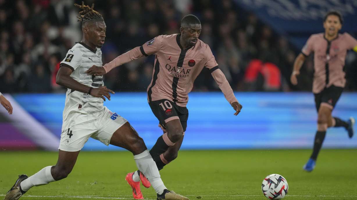 PSG's Ousmane Dembele, center, duels for the ball with Rennes' Christopher Wooh during the French League One soccer match between Paris Saint-Germain and Rennes at the Parc des Princes in Paris, Friday, Sept. 27, 2024.