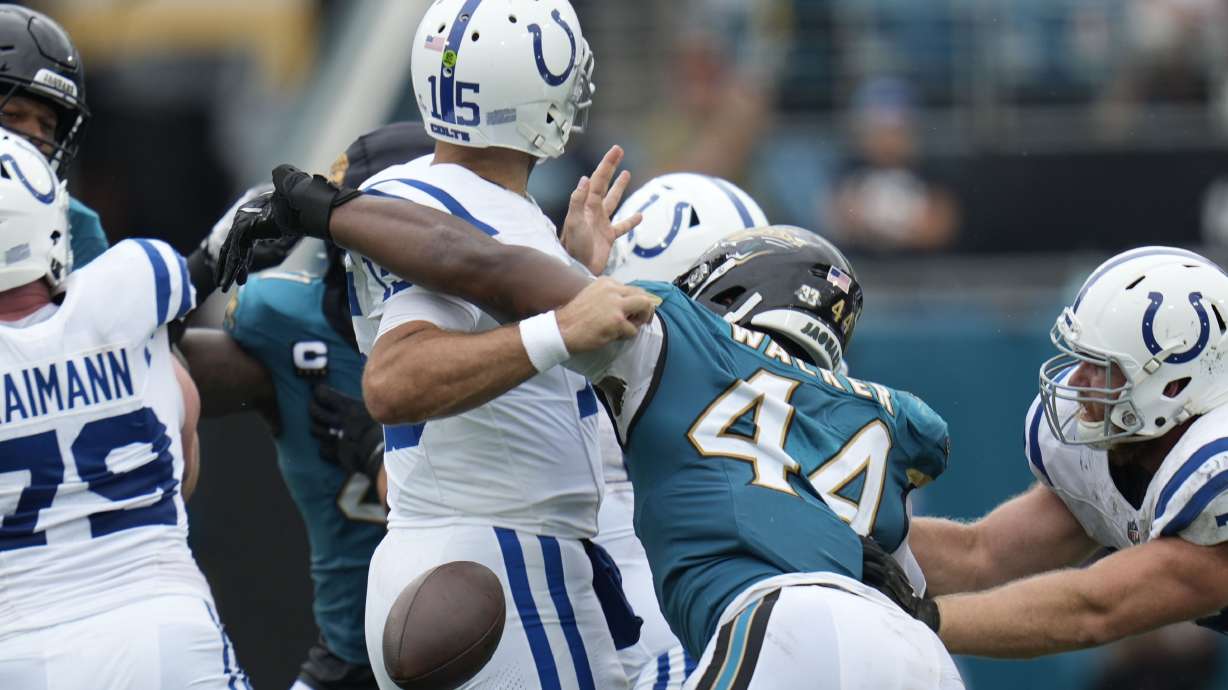 Indianapolis Colts quarterback Joe Flacco (15) fumbles as he is hit by Jacksonville Jaguars' Travon Walker (44) during the first half of an NFL football game, Sunday, Oct. 6, 2024, in Jacksonville, Fla.