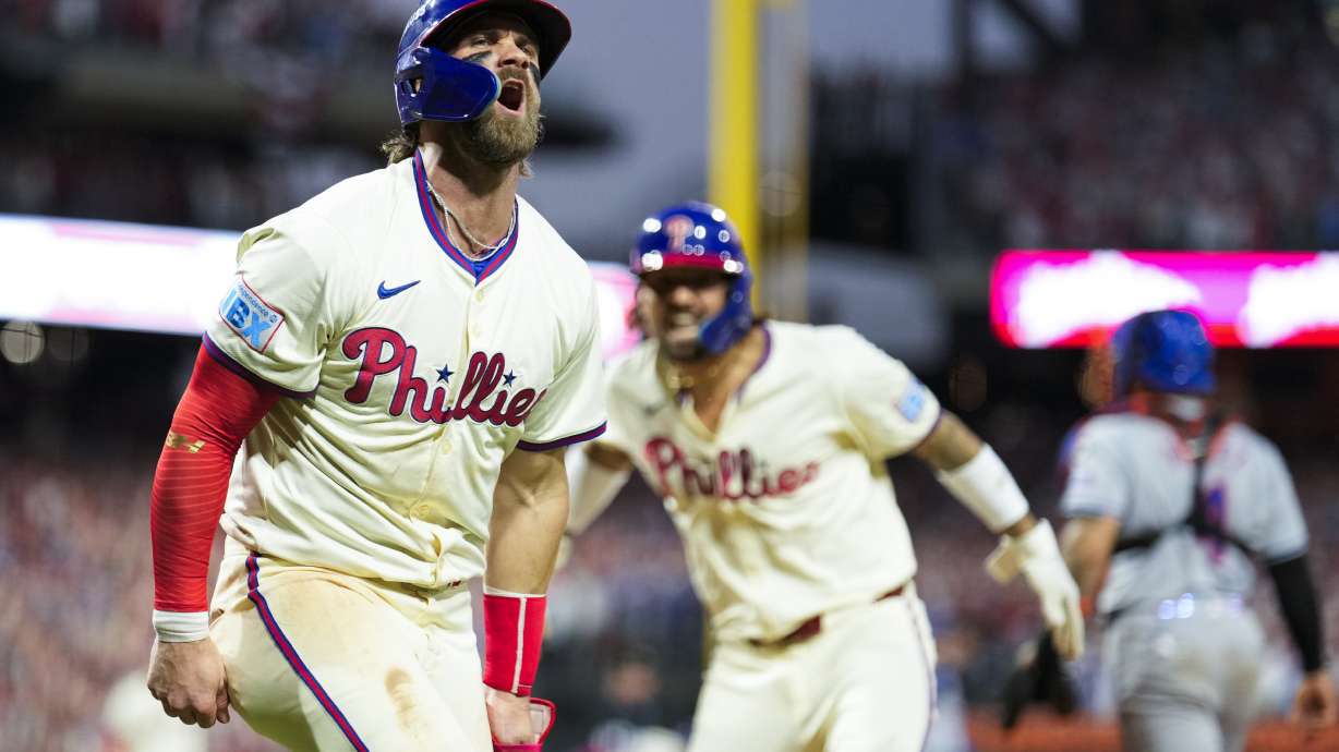 Philadelphia Phillies' Bryce Harper, left, and Nick Castellanos celebrate after scoringon a two-run triple hit by Bryson Stott during the eighth inning of Game 2 of a baseball NL Division Series against the New York Mets, Sunday, Oct. 6, 2024, in Philadelphia.