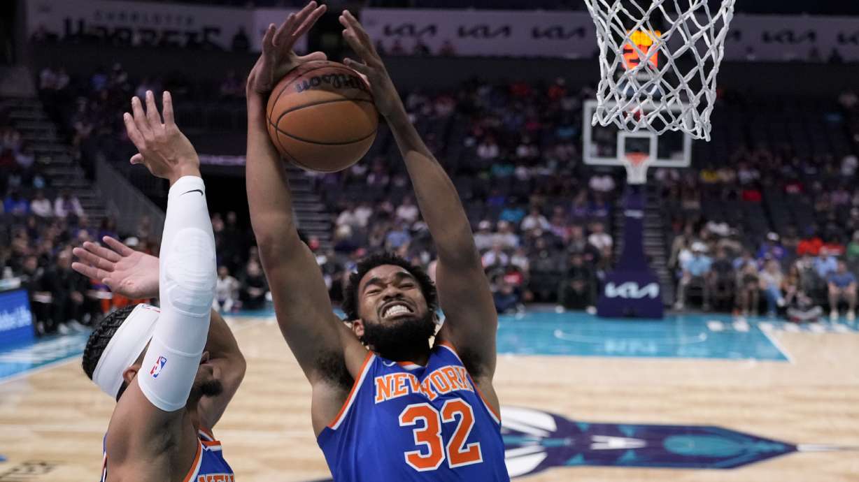 New York Knicks center Karl-Anthony Towns pulls down a rebound as guard Josh Hart looks on during the first half of a preseason NBA basketball game against the Charlotte Hornets, Sunday, Oct. 6, 2024, in Charlotte, N.C.