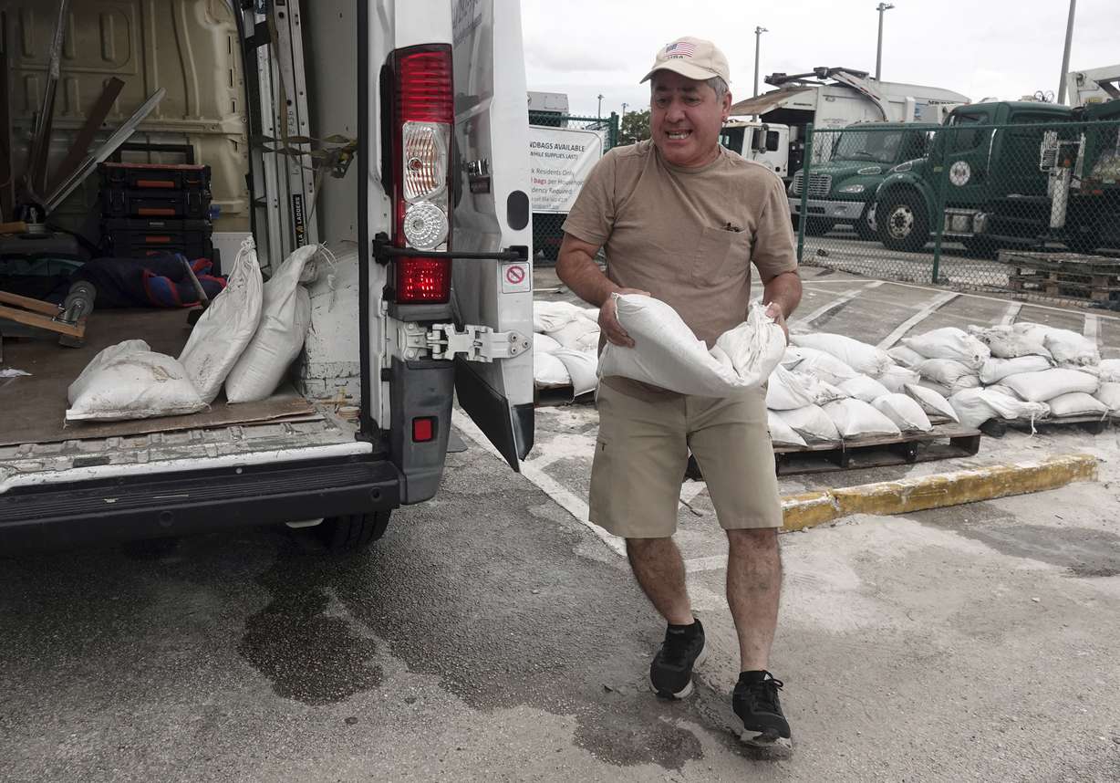Nelson Hoyos loads sandbags for his business in Oakland Park, Fla., Sunday, as Florida is in for a wet week as the storm nears the west coast.