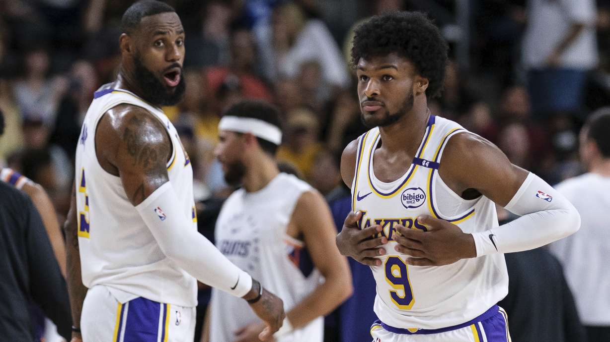 Los Angeles Lakers guard Bronny James (9), right, steps onto the court with Los Angeles Lakers forward LeBron James (23) during the first half of a preseason NBA basketball game Sunday, Oct. 6, 2024, in Palm Desert, Calif.