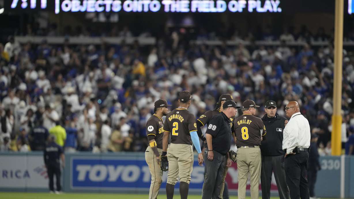 San Diego Padres manager Mike Shildt (8) and players talk to umpires after items were thrown on the field by fans during the seventh inning in Game 2 of a baseball NL Division Series against the Los Angeles Dodgers, Sunday, Oct. 6, 2024, in Los Angeles.