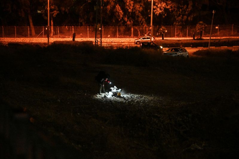 An Israeli police officer inspects the remains of a projectile after a rocket was fired from Lebanon and landed in Israel, amid cross-border hostilities between Hezbollah and Israel, in Haifa, Israel, Oct. 7.