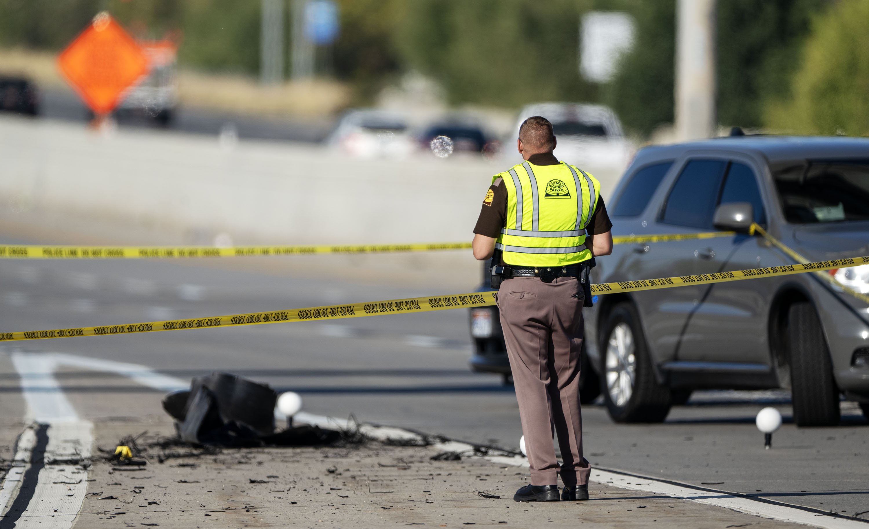 A Utah Highway Patrol trooper looks over the scene as law enforcement officials investigate a fatal road rage shooting on state Route 201 near 1000 West in Salt Lake City on Monday, Oct. 7.