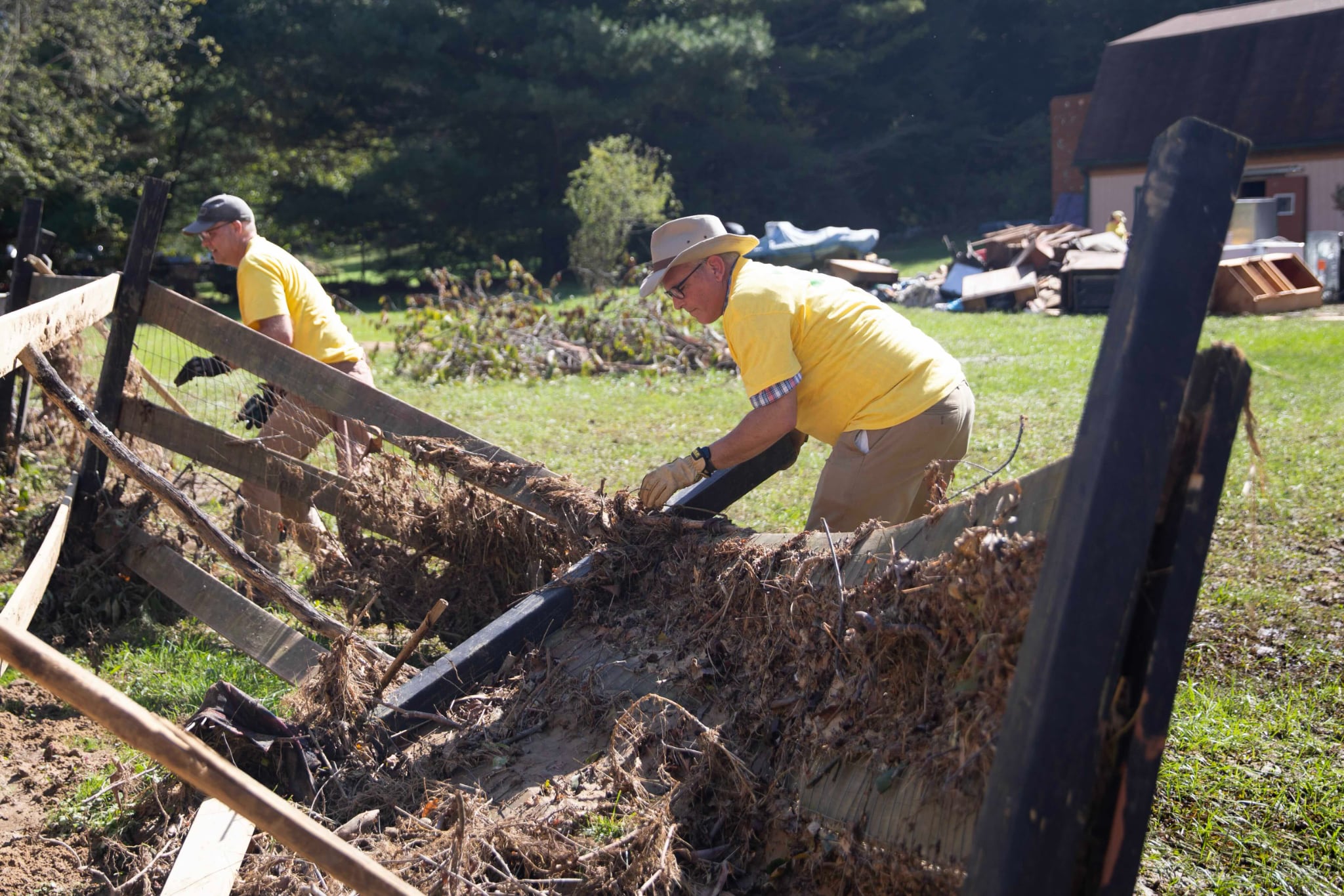 Volunteers from The Church of Jesus Christ of Latter-day Saints help tear down a broken fence at Carolyn Ward’s home in Fairview, North Carolina, on Saturday.