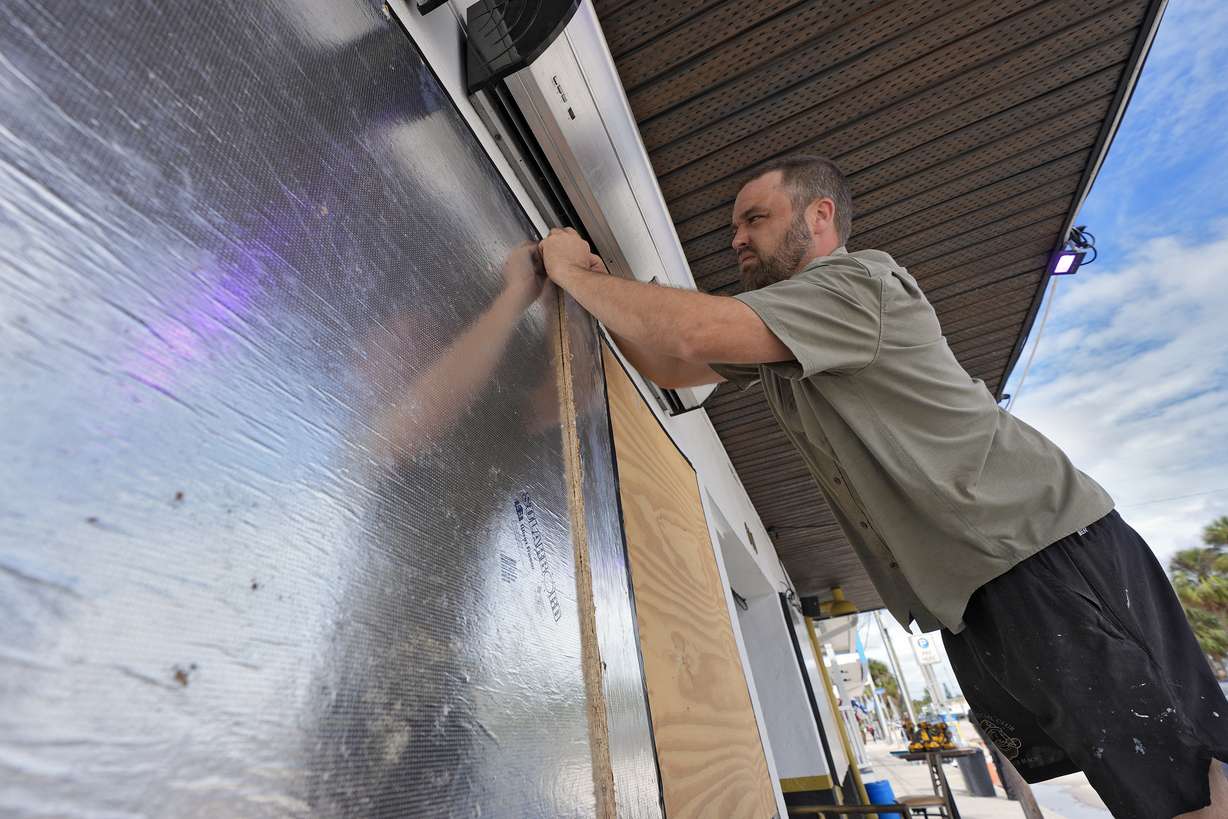 Rob Menard, owner of Reefers Social Club, finishes putting up boards and tape over windows Monday, in Clearwater Beach, Fla., ahead of the possible arrival of Hurricane Milton.