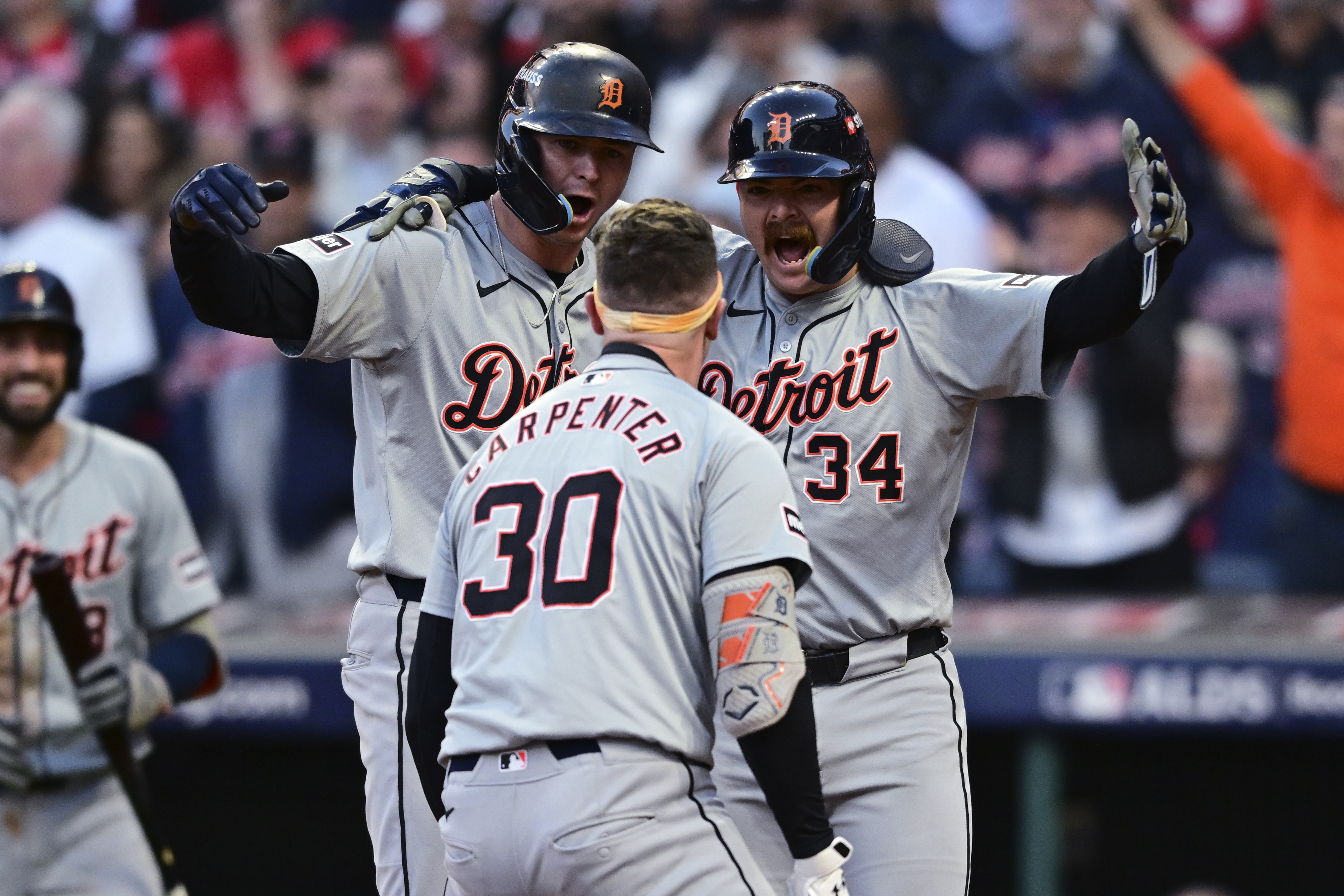Detroit Tigers' Trey Sweeney (27) and Jake Rogers wait at home plate for teammate Kerry Carpenter (30) after Carpenter hit a three-run home run in the ninth inning during Game 2 of baseball's AL Division Series against the Cleveland Guardians, Monday, Oct. 7, 2024, in Cleveland.