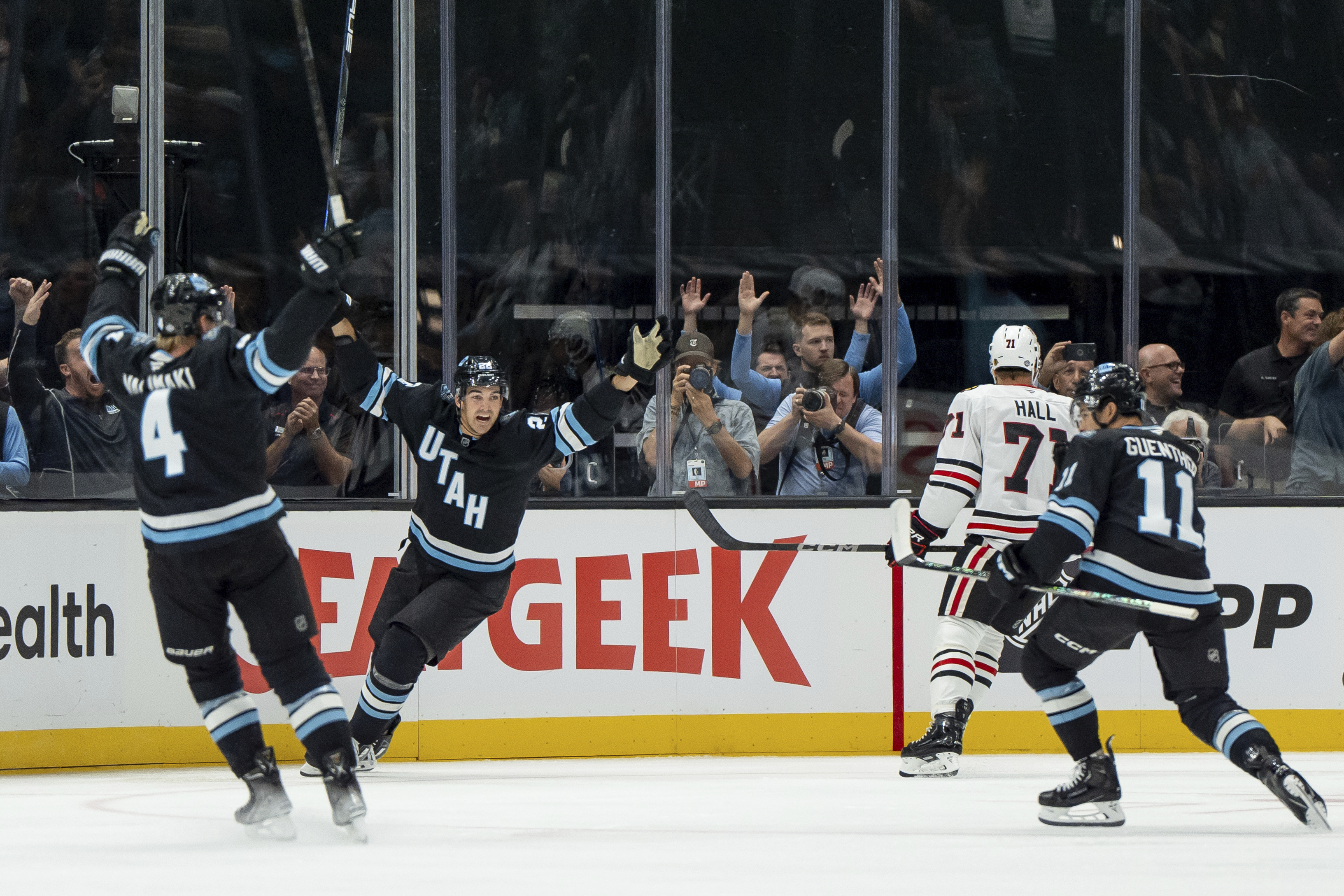 Utah Hockey Club defenseman Juuso Valimaki (4), center Jack McBain, second from left, and right wing Dylan Guenther (11) celebrate after Guenther scored during the first period of an NHL hockey game against the Chicago Blackhawks, Tuesday, Oct. 8, 2024, in Salt Lake City.
