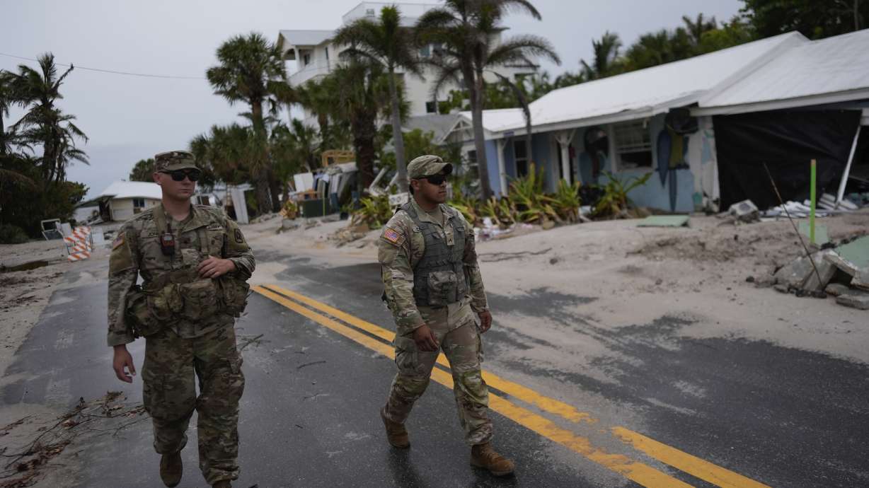 Members of the Florida Army National Guard walk past a home slated for demolition after it was damaged in Hurricane Helene, as they check for any remaining residents, ahead of the arrival of Hurricane Milton, Tuesday on Anna Maria Island, Fla.