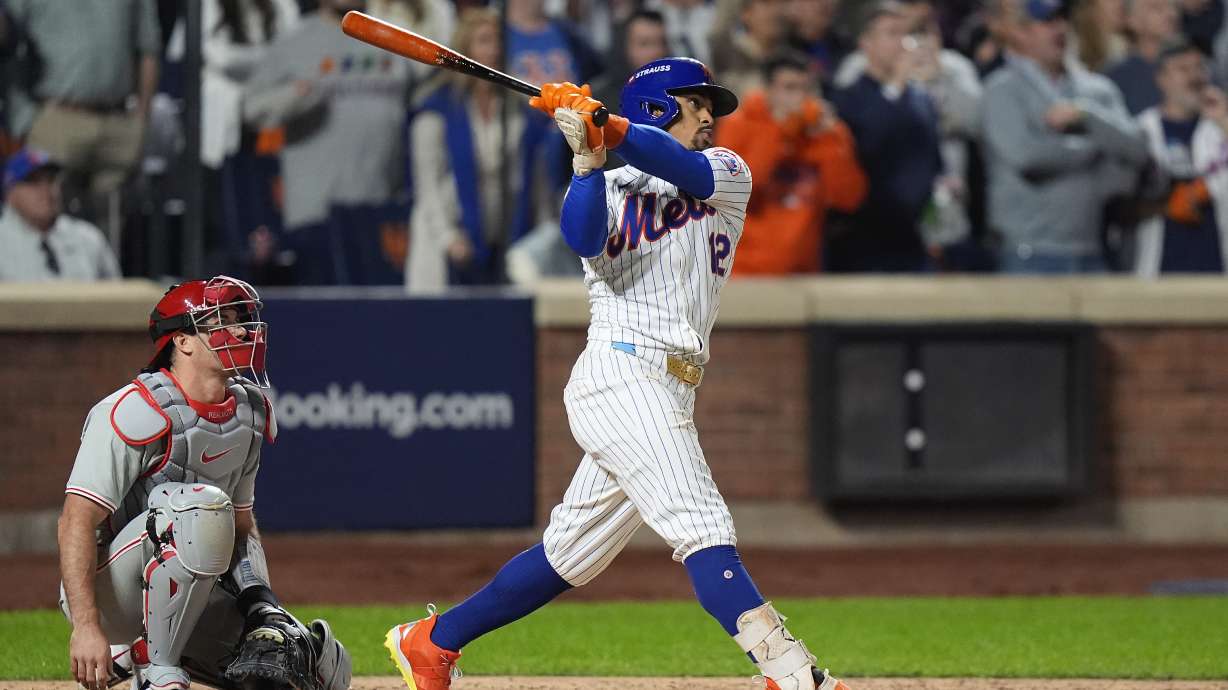 New York Mets' Francisco Lindor (12) follows through on a grand slam home run against the Philadelphia Phillies during the sixth inning of Game 4 of the National League baseball playoff series, Wednesday, Oct. 9, 2024, in New York.
