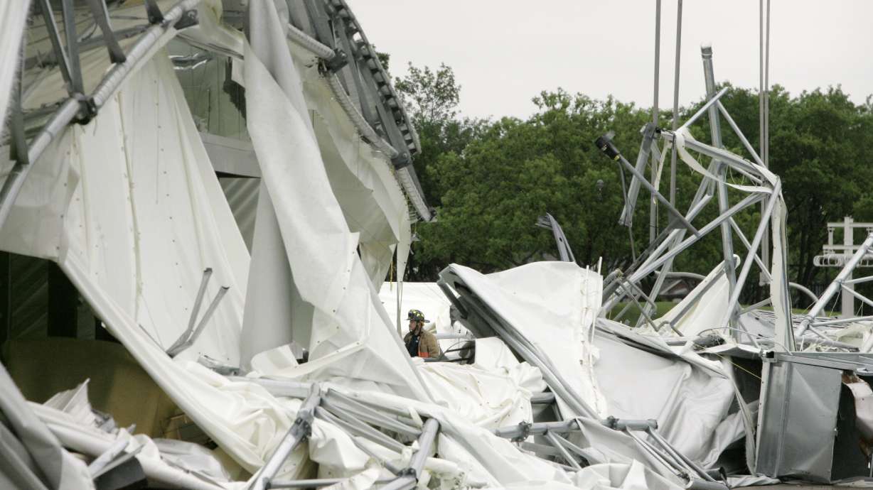 FILE - A fire fighter, center, stands surrounded by the collapsed canopy that covered the Dallas Cowboys indoor practice facility in Irving, Texas, on May 2, 2009.