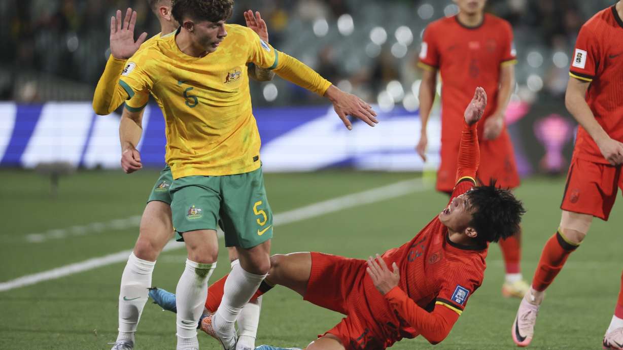 China's Hu Hetao reacts after a collision with Australia's Jordan Bos, left, during the World Cup 2026 Group C qualifying soccer match between Australia and China at Adelaide Oval, Adelaide, Australia, Thursday Oct. 10, 2024.