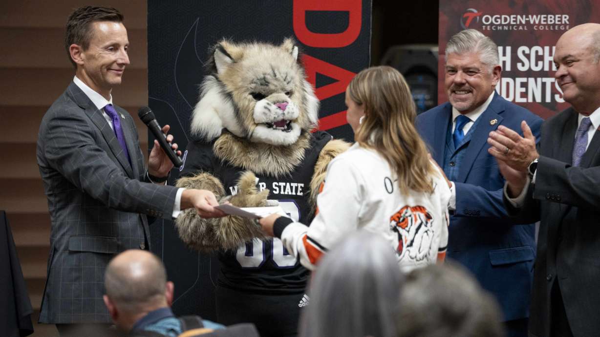 Area college and university presidents present Ogden High School senior Grace Malan with an acceptance letter at the launch of an initiative on Thursday to automatically admit seniors in Davis, Morgan, and Weber counties.