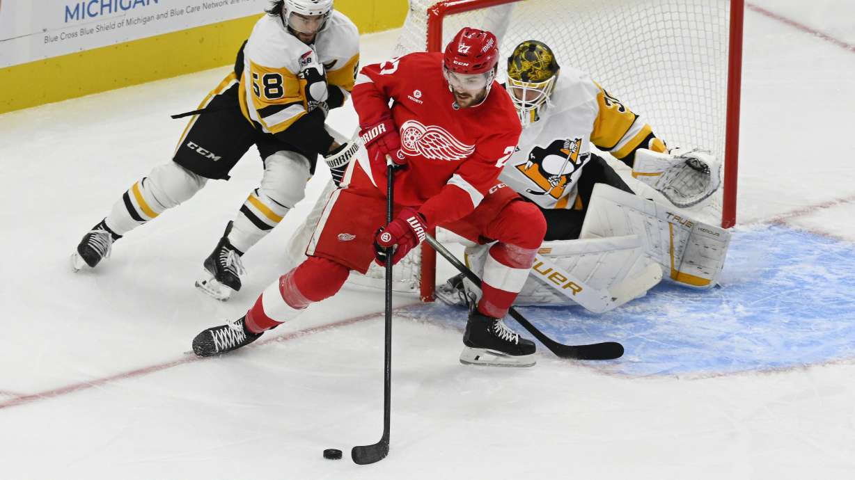 Detroit Red Wings center Michael Rasmussen, front, keeps the puck away from Pittsburgh Penguins defenseman Kris Letang (58) as goaltender Joel Blomqvist looks on during the first period of an NHL hockey game, Thursday, Oct. 10, 2024, in Detroit.