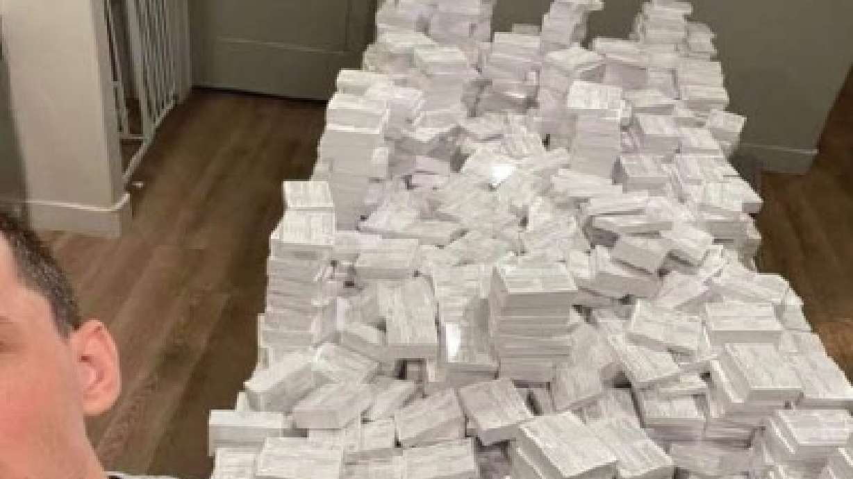 Nicholas Frank Sciotto poses next to piles of fake COVID-19 vaccination cards in 2021. The Salt Lake man was sentenced to a year in prison Thursday for selling over 120,000 of them during the pandemic.