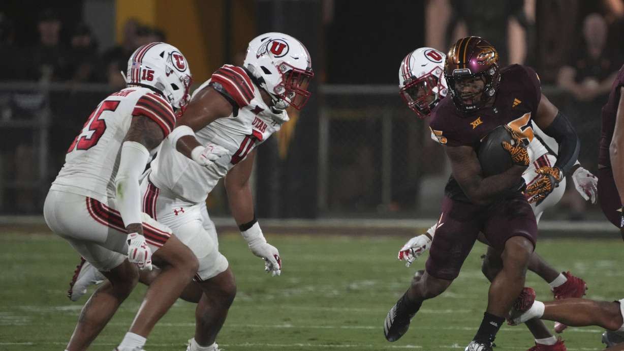 Arizona State running back DeCarlos Brooks runs away from Utah defensive end Logan Fano (0) and safety Tao Johnson (15) in the first half during an NCAA college football game, Friday, Oct. 11, 2024, in Tempe, Ariz.
