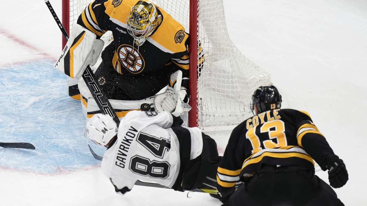 Boston Bruins' Jeremy Swayman (1) blocks a shot by Los Angeles Kings' Vladislav Gavrikov (84) as Charlie Coyle (13) defends in overtime during an NHL hockey game, Saturday, Oct. 12, 2024, in Boston.