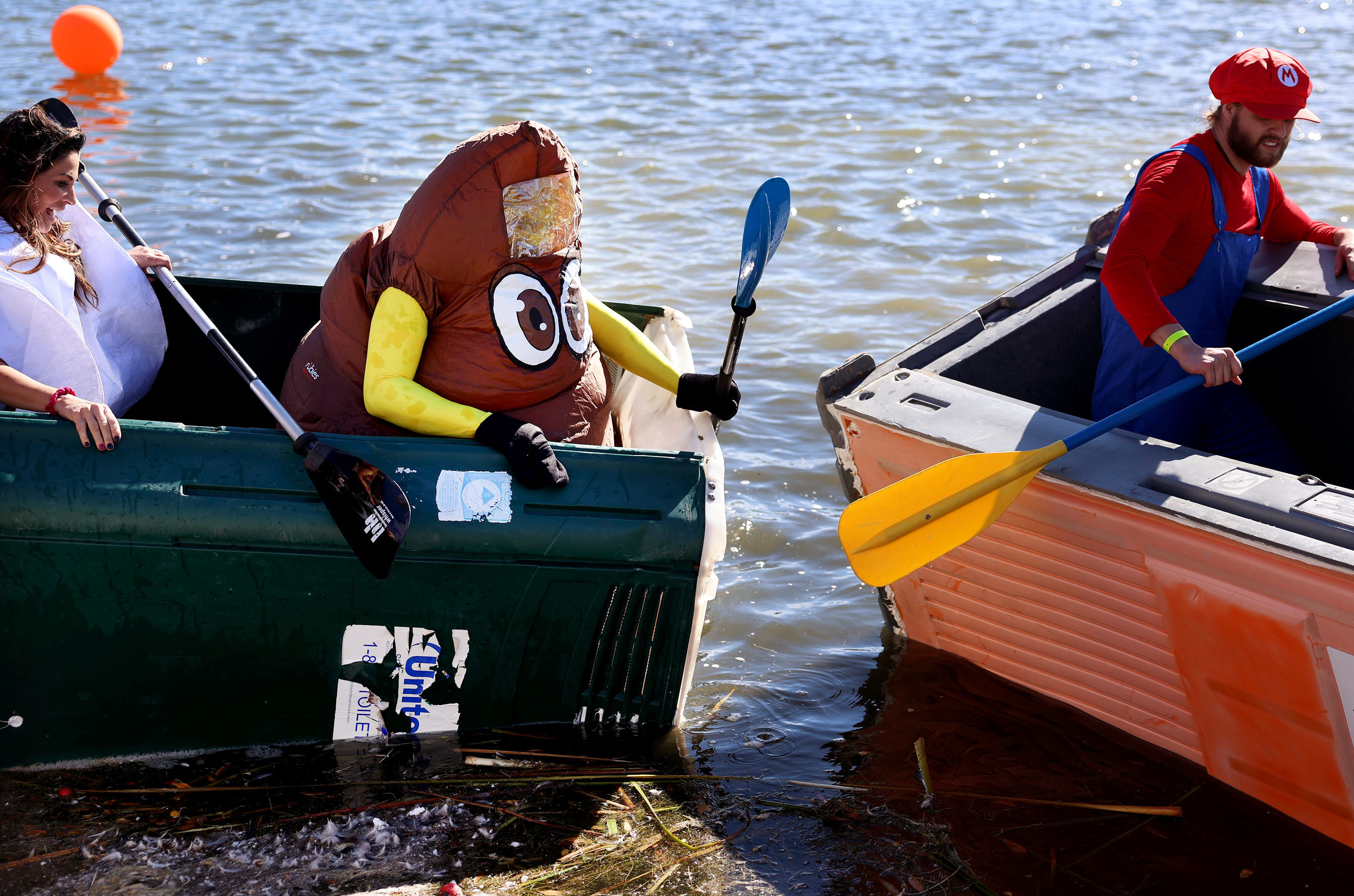 Clint Nash, dressed as the poop emoji, and Lindsay Bench, dressed as a roll of toilet paper, return to shore after racing in a port-a-potty at the LiveDAYBREAK Ginormous Pumpkin Regatta at Oquirrh Lake in South Jordan on Saturday, Oct. 12, 2024.