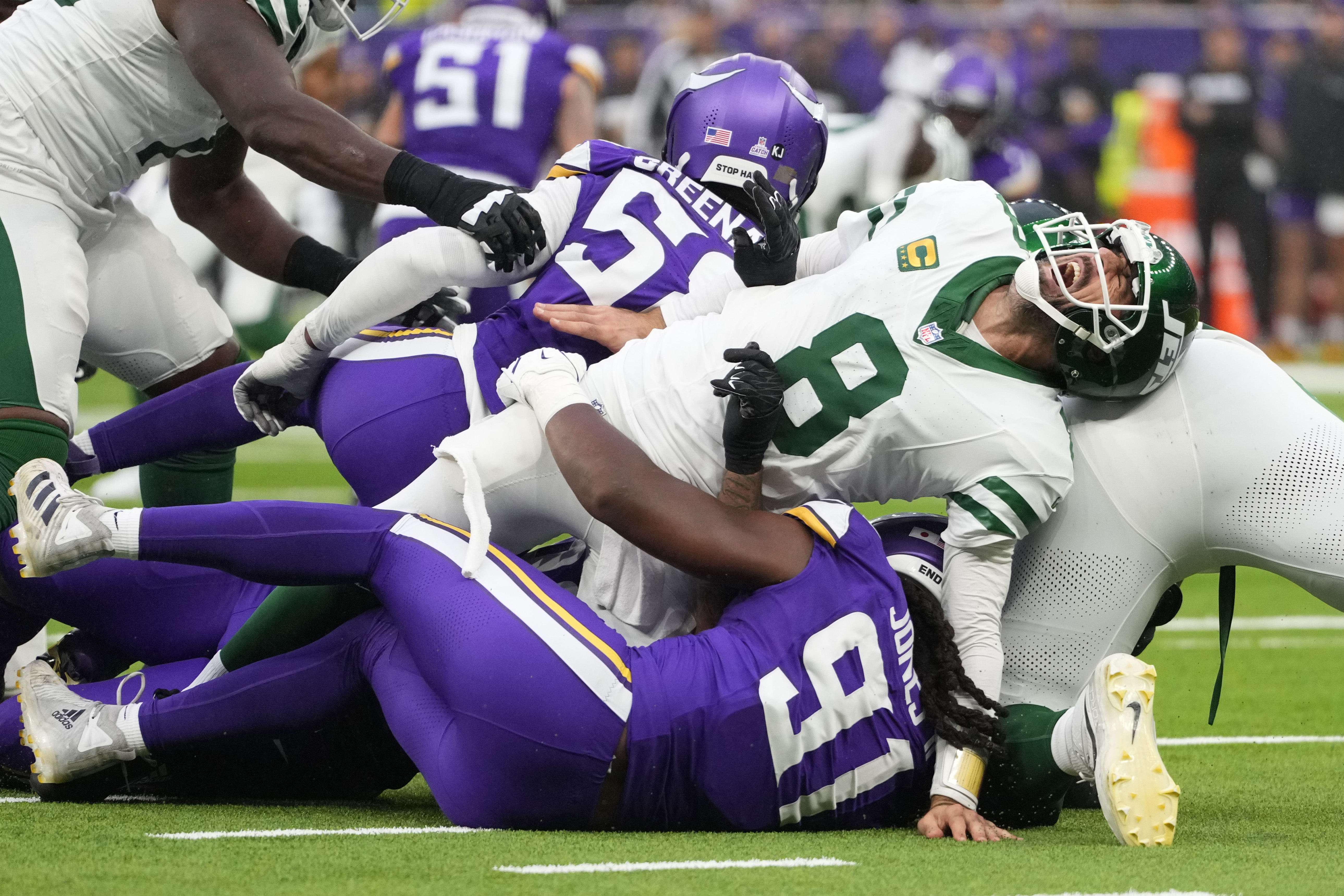 New York Jets quarterback Aaron Rodgers (8), right, reacts as he is tackled during the second half of an NFL football game against the Minnesota Vikings, Sunday, Oct. 6, 2024, at the Tottenham Hotspur stadium in London.