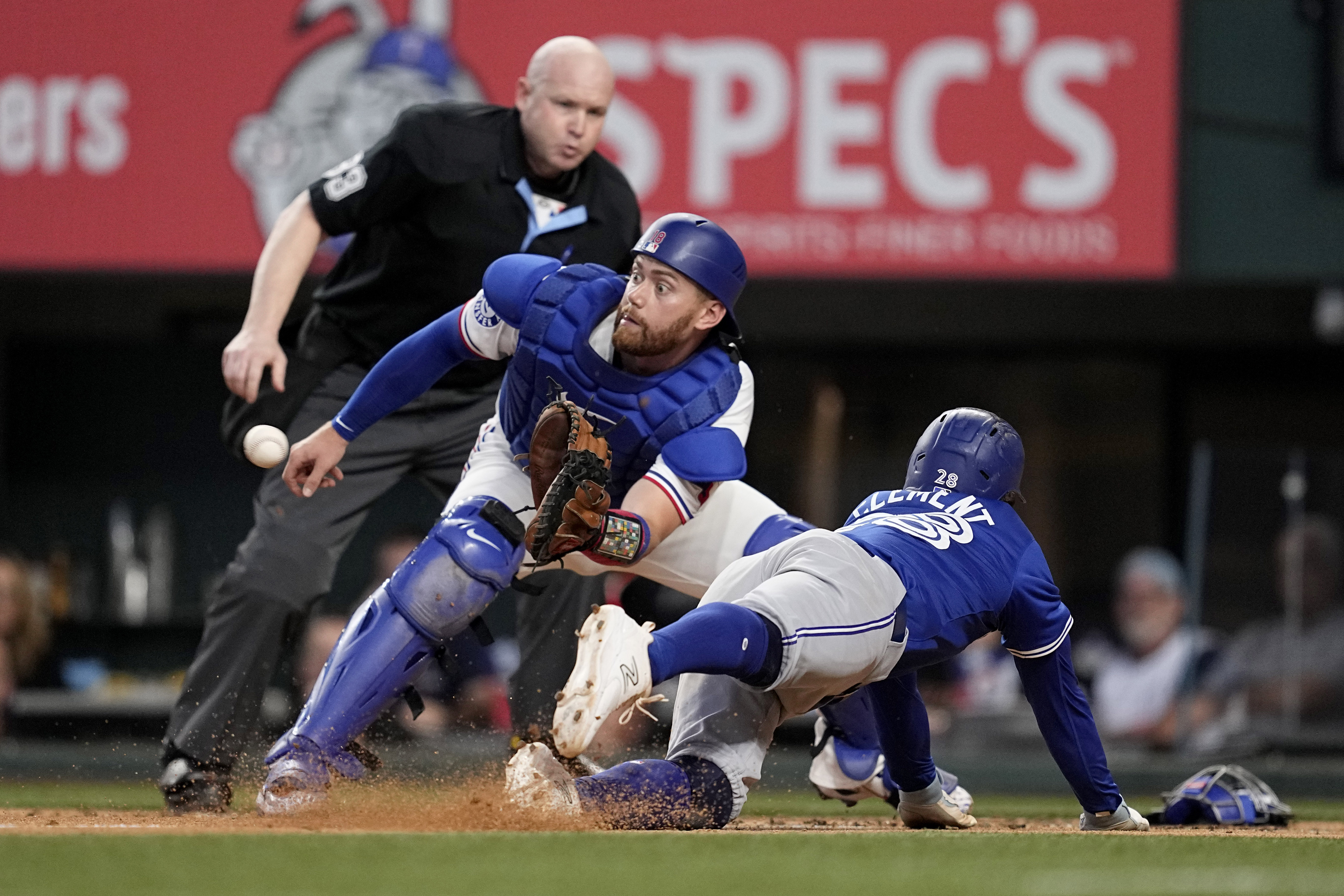 Texas Rangers catcher Carson Kelly reaches out for the throw before tagging out Toronto Blue Jays' Ernie Clement, right, who was trying to score on a Vladimir Guerrero Jr. single as umpire Mike Estabrook, rear, looks on in the fourth inning of a baseball game in Arlington, Texas, Thursday, Sept. 19, 2024.