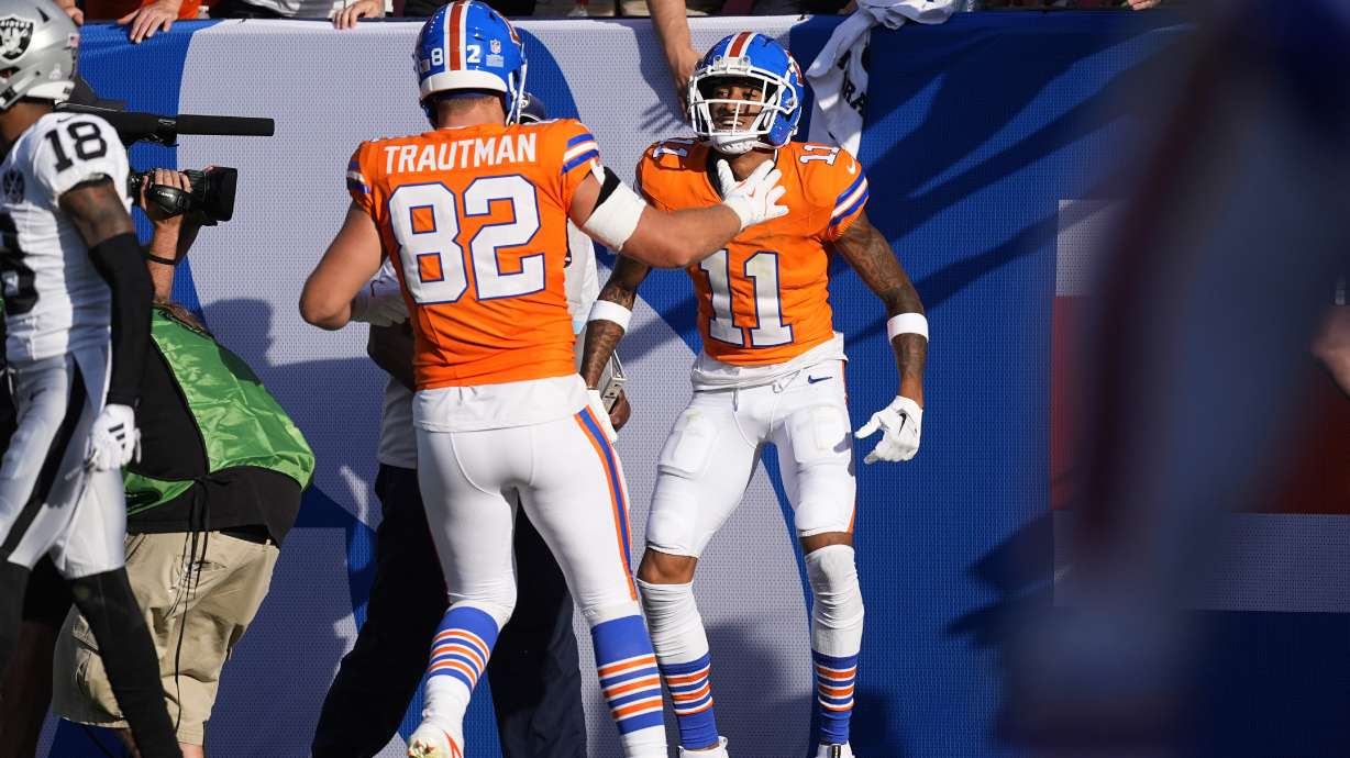 Denver Broncos tight end Adam Trautman, front, congratulates wide receiver Josh Reynolds after his touchdown catch in the second half of an NFL football game against the Las Vegas Raiders, Sunday, Oct. 6, 2024, in Denver.