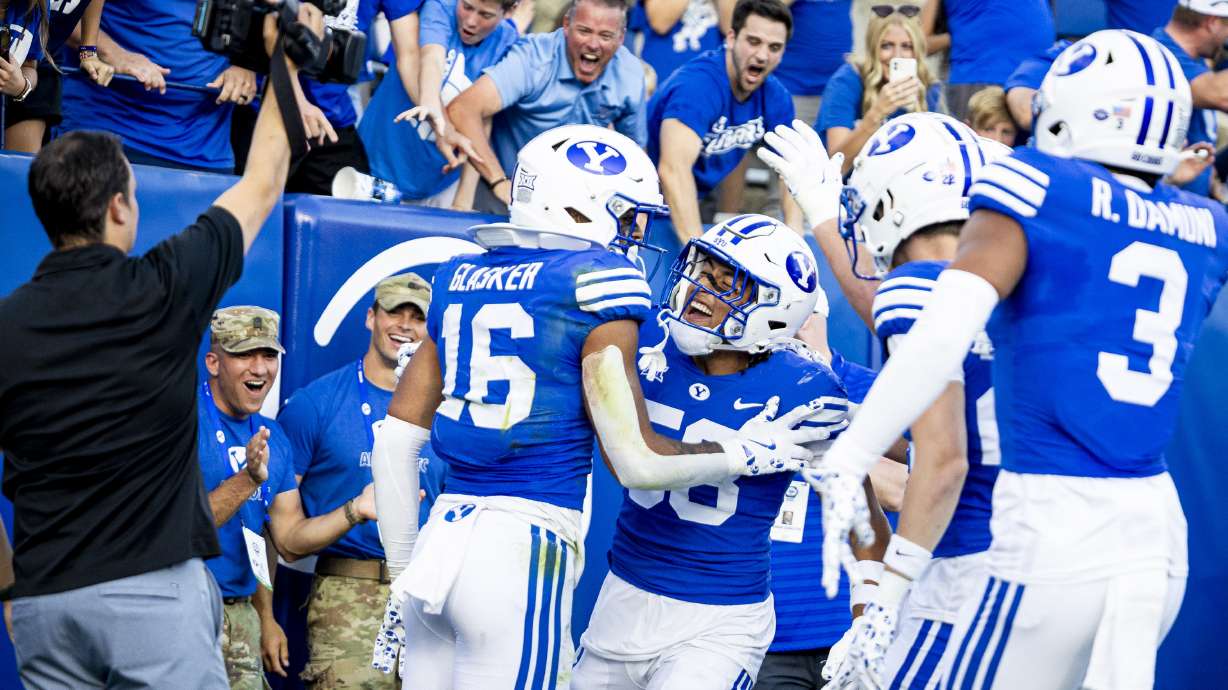 BYU linebacker Aisea Moa (58) and fellow linebacker Isaiah Glasker (16) celebrate Glasker’s interception that led to a touchdown against the Arizona Wildcats during a game held at LaVell Edwards Stadium in Provo on Saturday, Oct. 12, 2024.