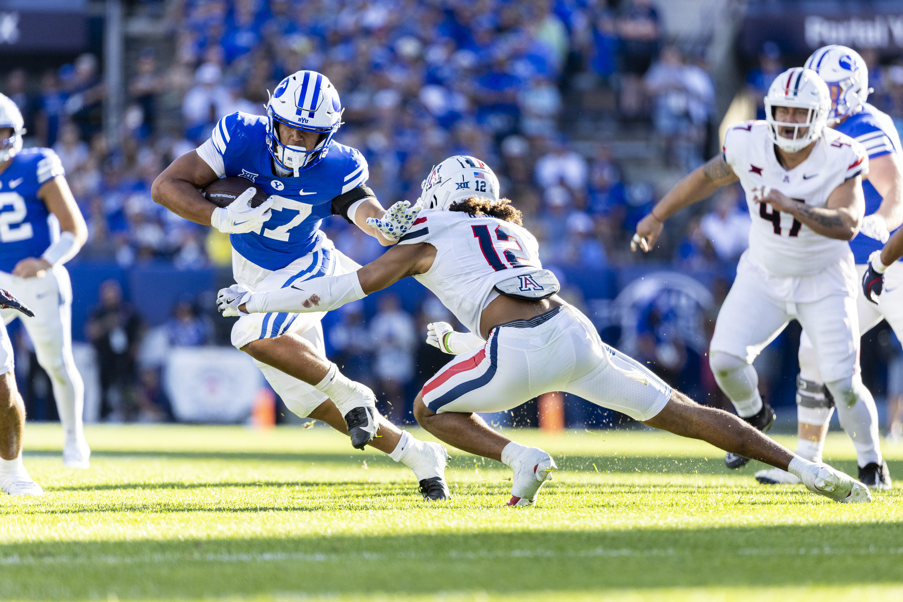 BYU running back LJ Martin (27) runs the ball as he tries to stiff-arm Arizona Wildcats defensive back Genesis Smith (12) during a game held at LaVell Edwards Stadium in Provo on Saturday, Oct. 12, 2024.