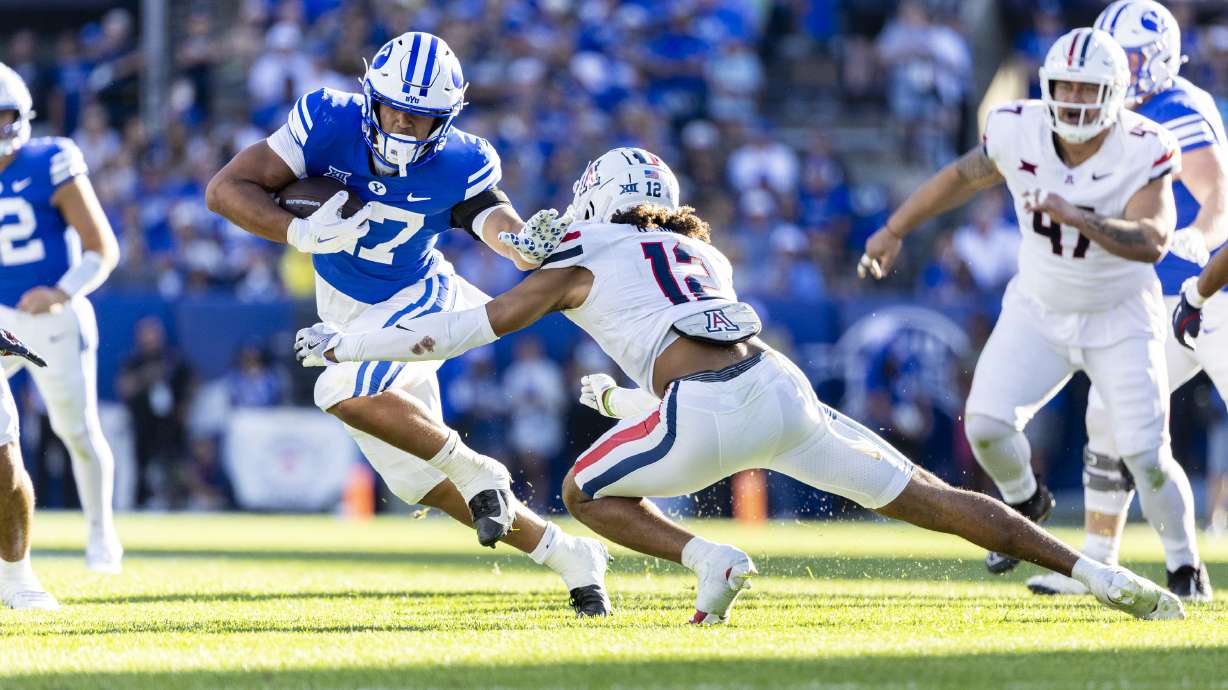 BYU running back LJ Martin (27) runs the ball as he tries to stiff-arm Arizona Wildcats defensive back Genesis Smith (12) during a game held at LaVell Edwards Stadium in Provo on Saturday, Oct. 12, 2024.