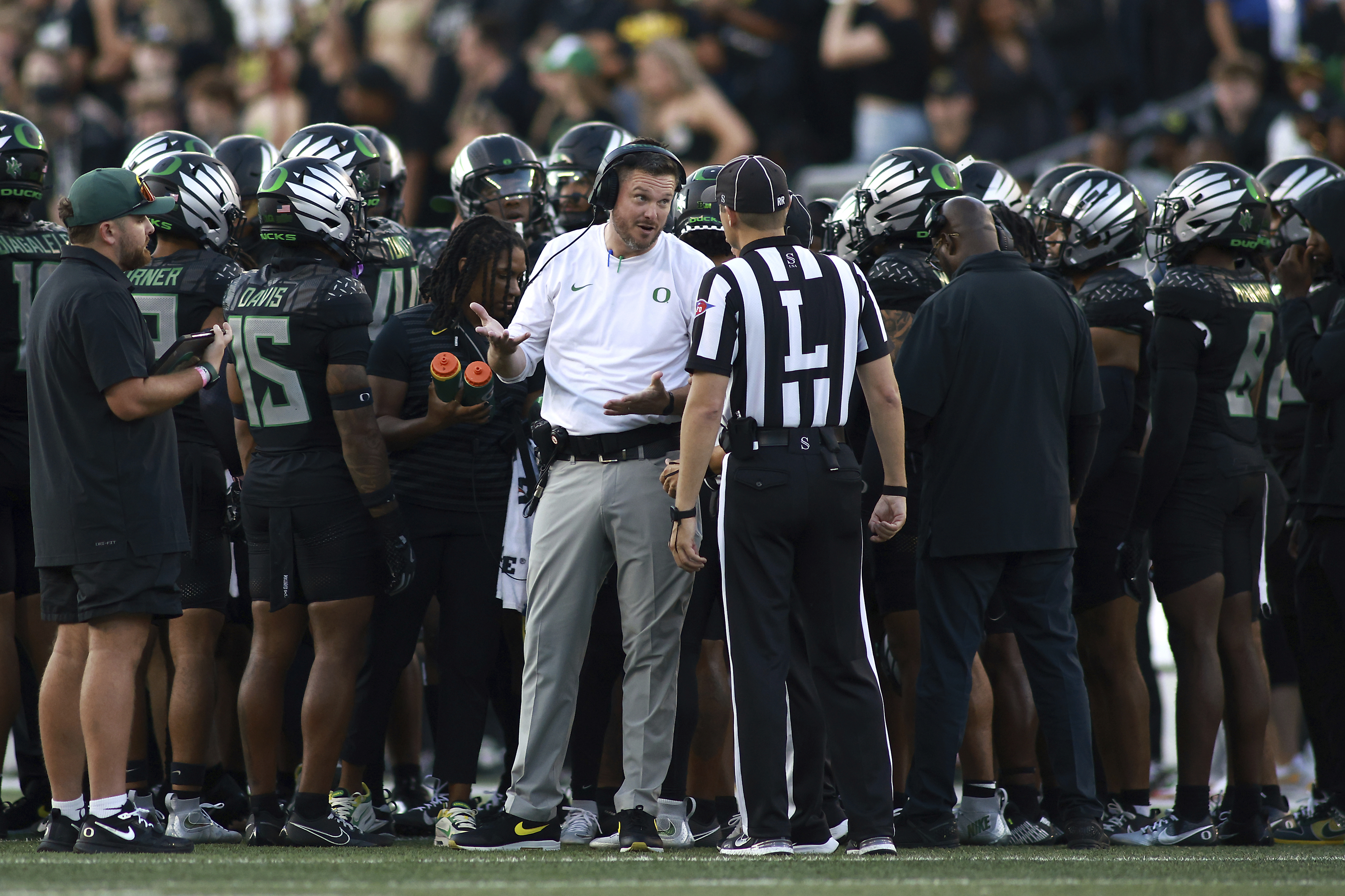 Oregon head coach Dan Lanning, center left, talks with a referee, center right, during an NCAA college football game against Ohio State, Saturday, Oct. 12, 2024, in Eugene, Ore.