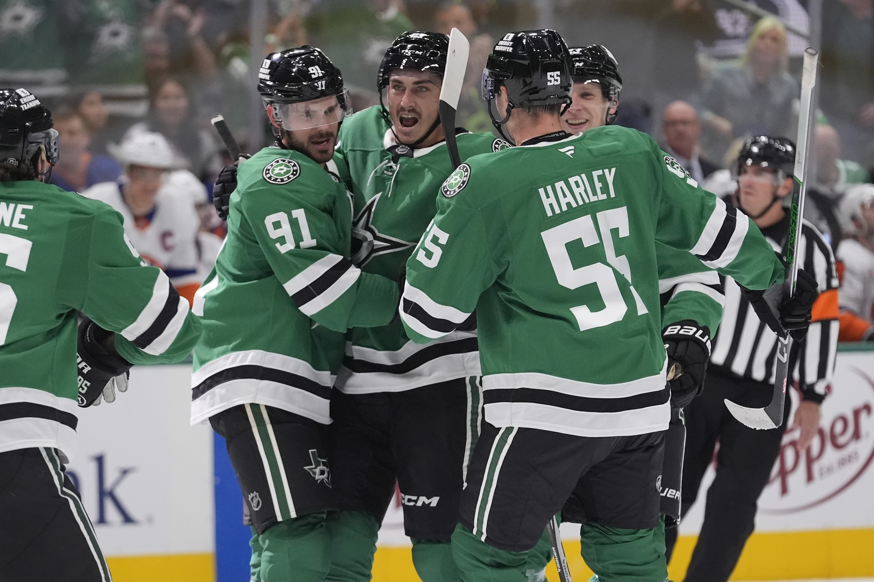 Dallas Stars center Tyler Seguin (91) hugs teammate Mason Marchment (27) to celebrate his goal with teammates Thomas Harley (55) and Esa Lindell (23) during the first period of an NHL hockey game against the New York Islanders Saturday, Oct. 12, 2024, in Dallas.