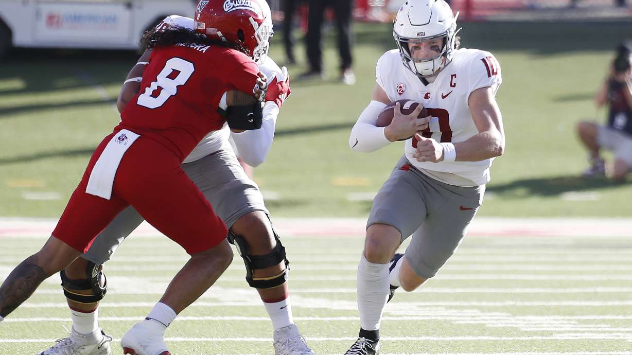 Washington State quarterback John Mateer heads through the line against Fresno State linebacker Tuasivi Nomura during the first half of an NCAA college football game in Fresno, Calif., Saturday, Oct. 12, 2024.