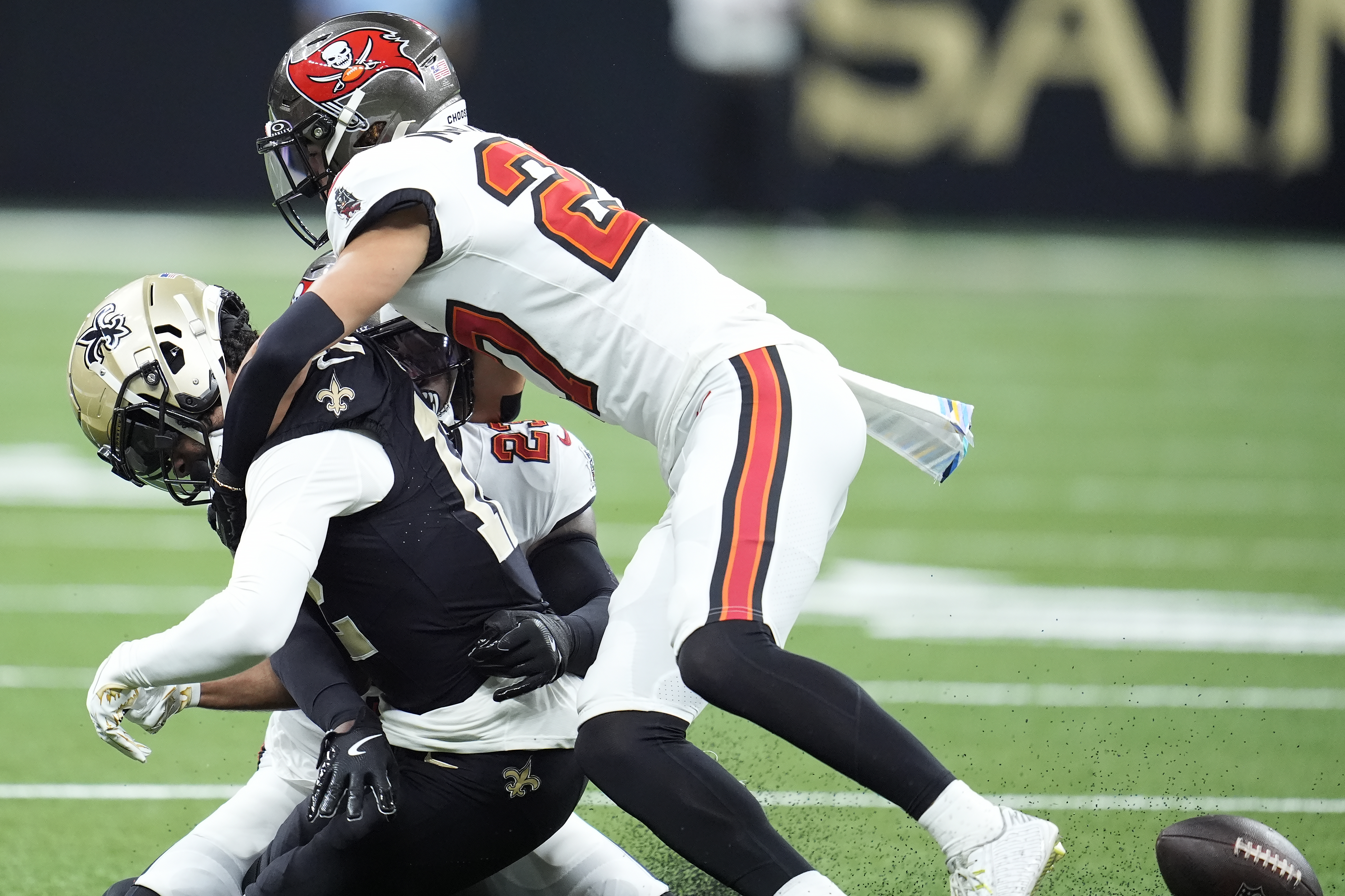New Orleans Saints wide receiver Chris Olave, left, fumbles the ball while hit by Tampa Bay Buccaneers cornerback Zyon McCollum, top, and safety Tykee Smith, rear, that Antoine Winfield Jr. returned for a touchdown, during the first half of an NFL football game in New Orleans, Sunday, Oct. 13, 2024.