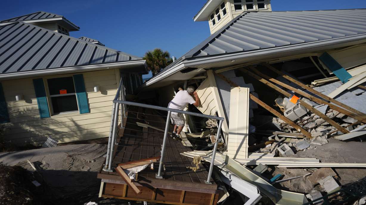 A property owner peers into the remains of the second floor unit where he lived while renting out the other units, on Manasota Key, in Englewood, Fla., on Sunday.