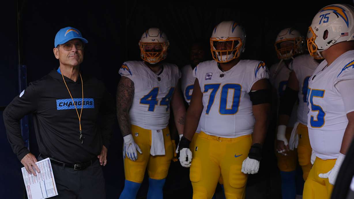 Los Angeles Chargers head coach Jim Harbaugh stands in a tunnel with players before an NFL football game against the Denver Broncos, Sunday, Oct. 13, 2024, in Denver.