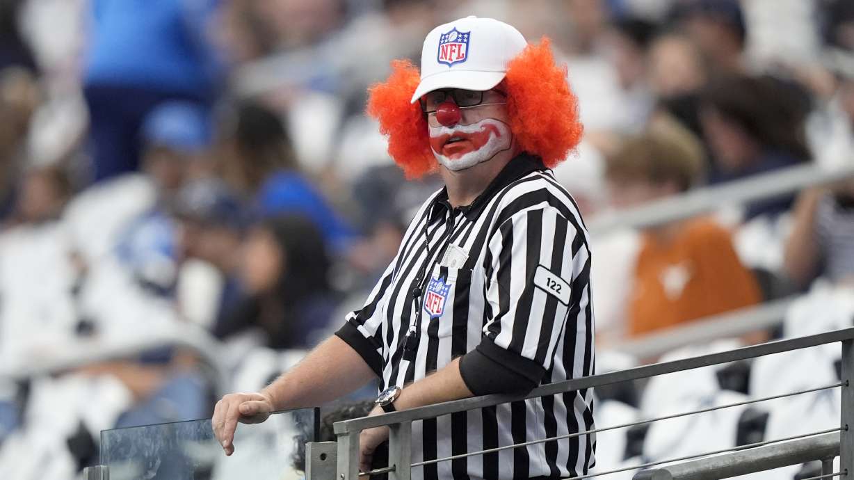 A fan dresses in a officials costume as he watches warmups before an NFL football game between the Detroit Lions and Dallas Cowboys in Arlington, Texas, Sunday, Oct. 13, 2024.