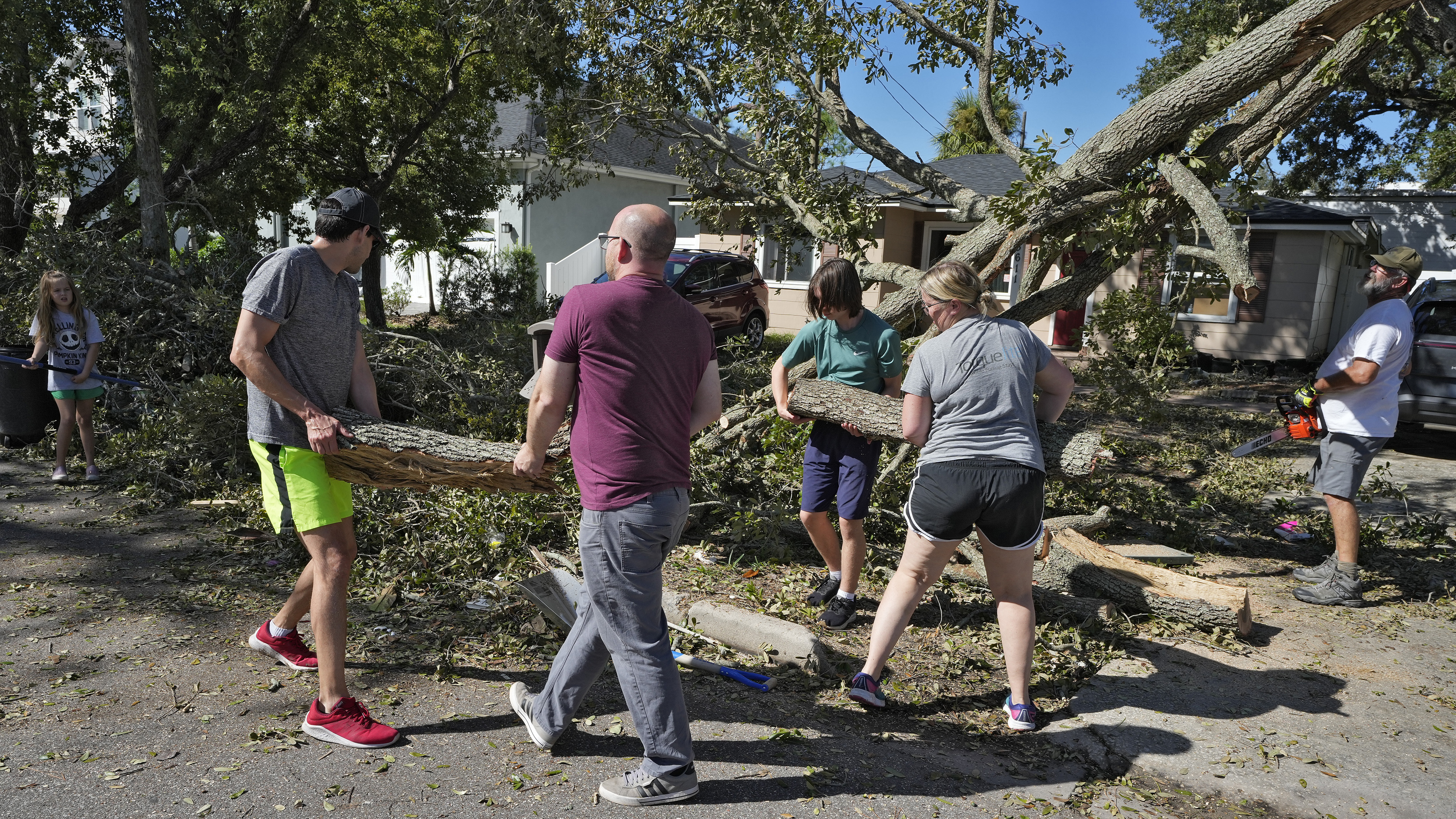 Neighbors help take down a tree felled by winds from Hurricane Milton, Sunday, in Tampa, Fla.
