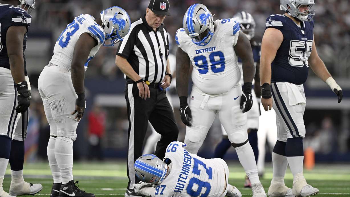 Detroit Lions' Aidan Hutchinson (97) is checked on by DJ Reader (98) and others after suffering an unknown injury in the second half of an NFL football game against the Dallas Cowboys in Arlington, Texas, Sunday, Oct. 13, 2024.